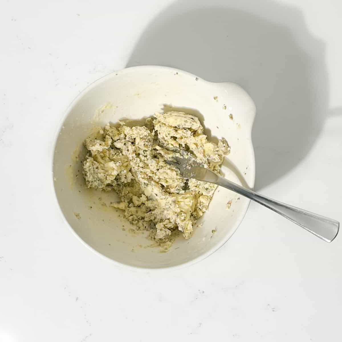 Compound butter for Greek roast chicken in a white bowl.