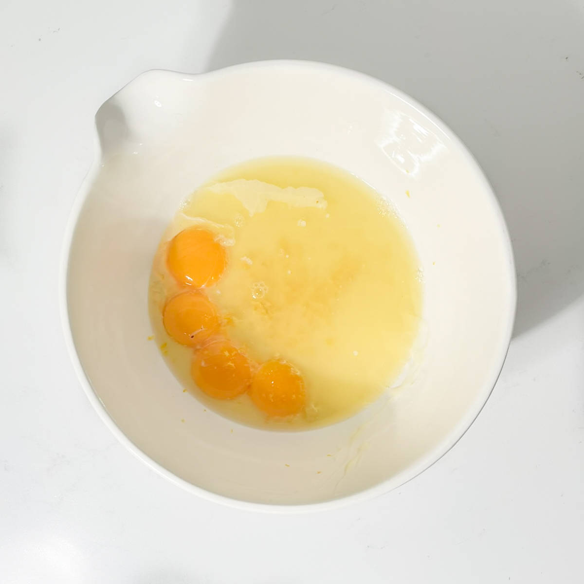 Eggs, condensed milk and lemon juice in a large white bowl.