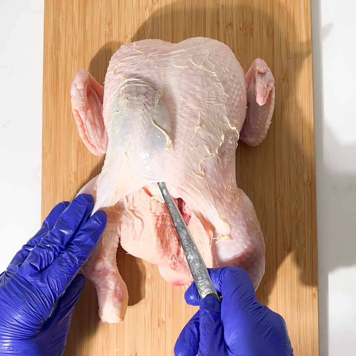 Loosening the chicken's skin with a spoon for the butter stuffing.