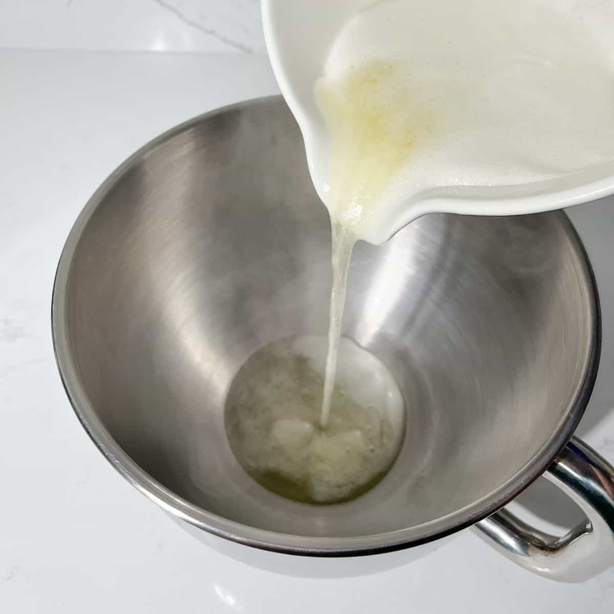 Pouring egg mixture into the bowl of a stand mixer.