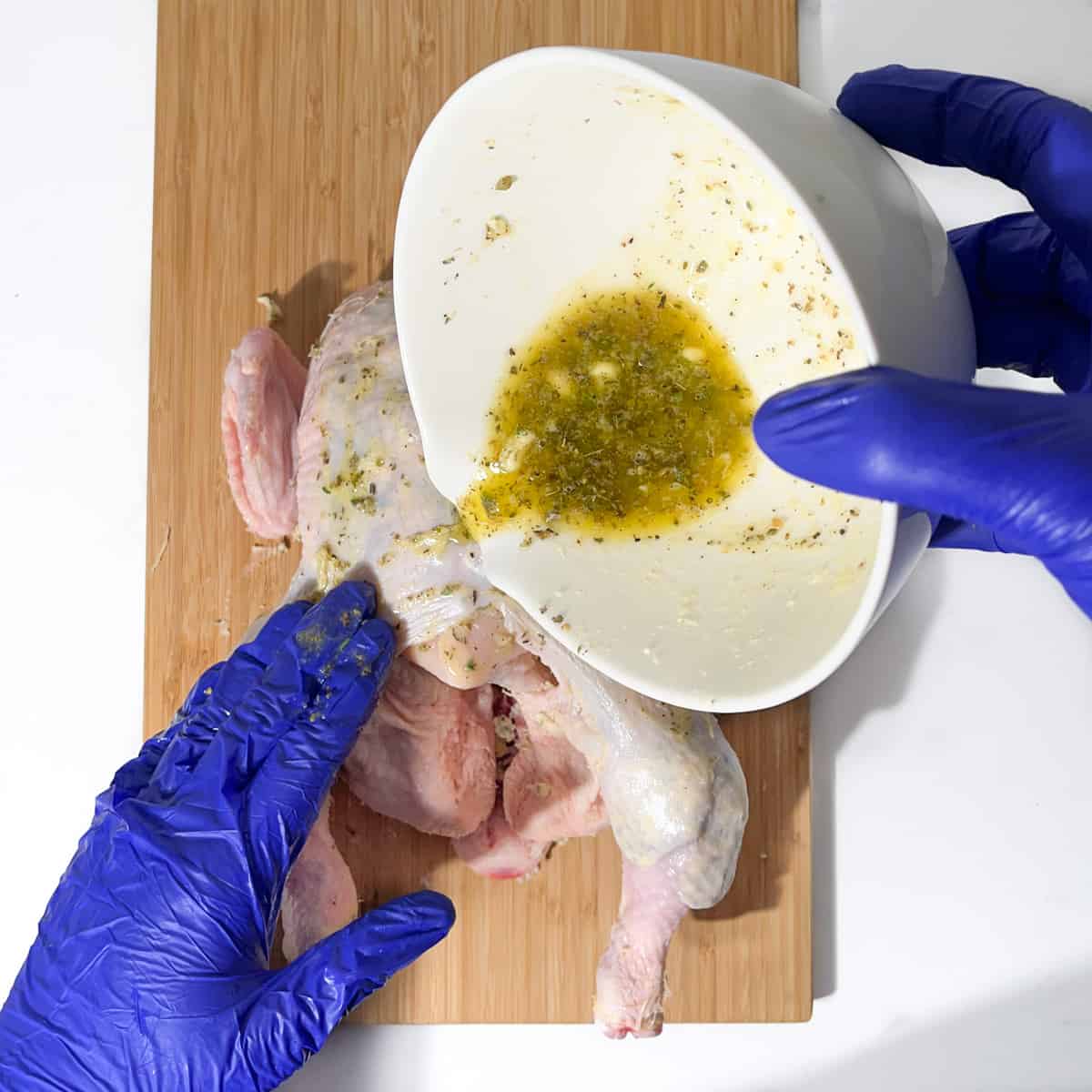 Pouring melted compound butter over the chicken.