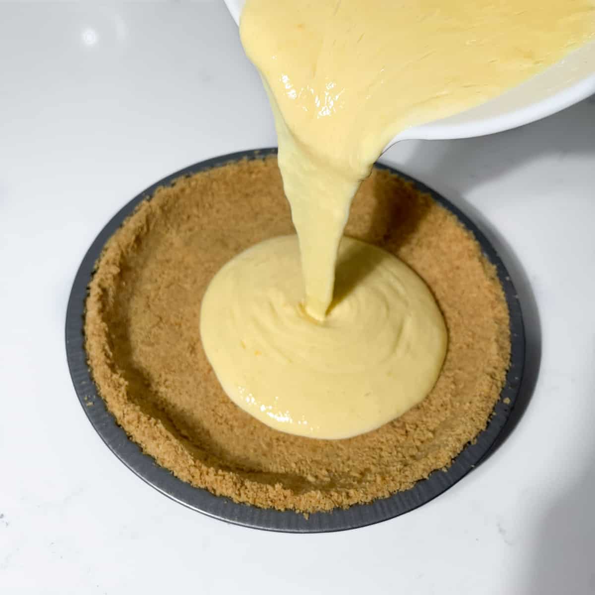 Pouring the lemon meringue filling into the pie base.