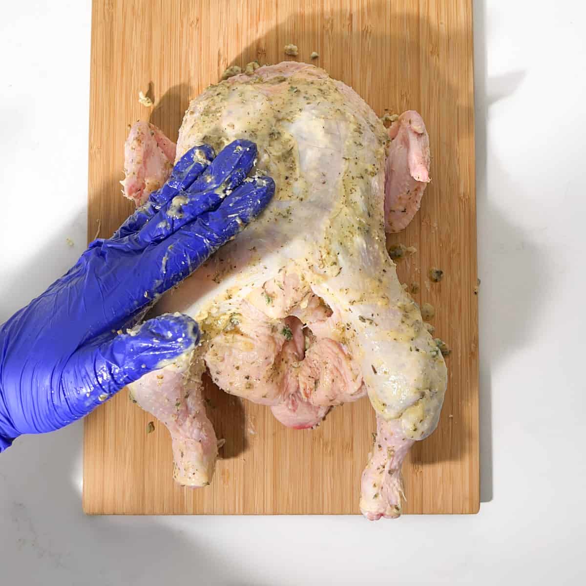 Rubbing butter over the Greek roast chicken.