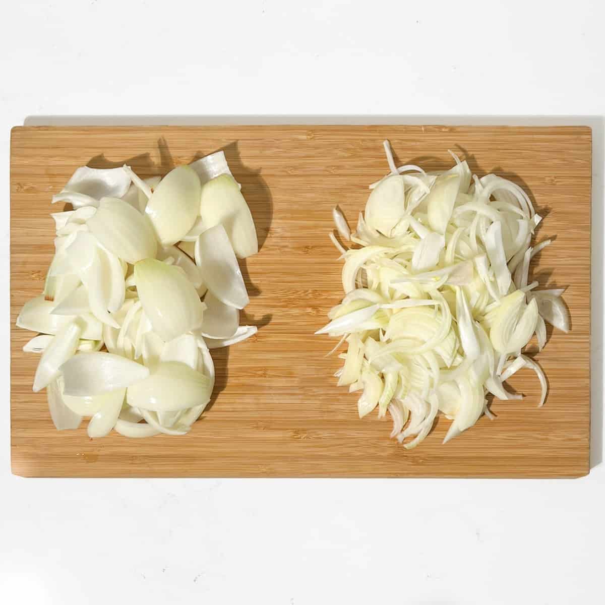 Sliced onions and onion petals in a large wooden chopping board.