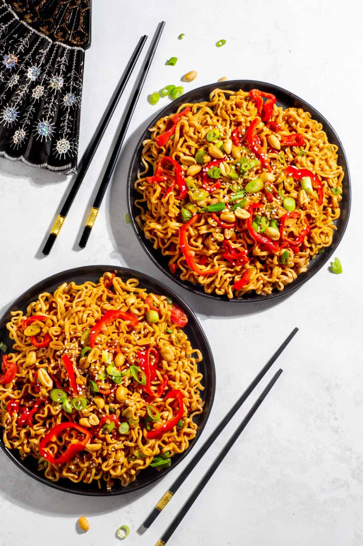 Sriracha noodles in two black bowls with chop sticks.