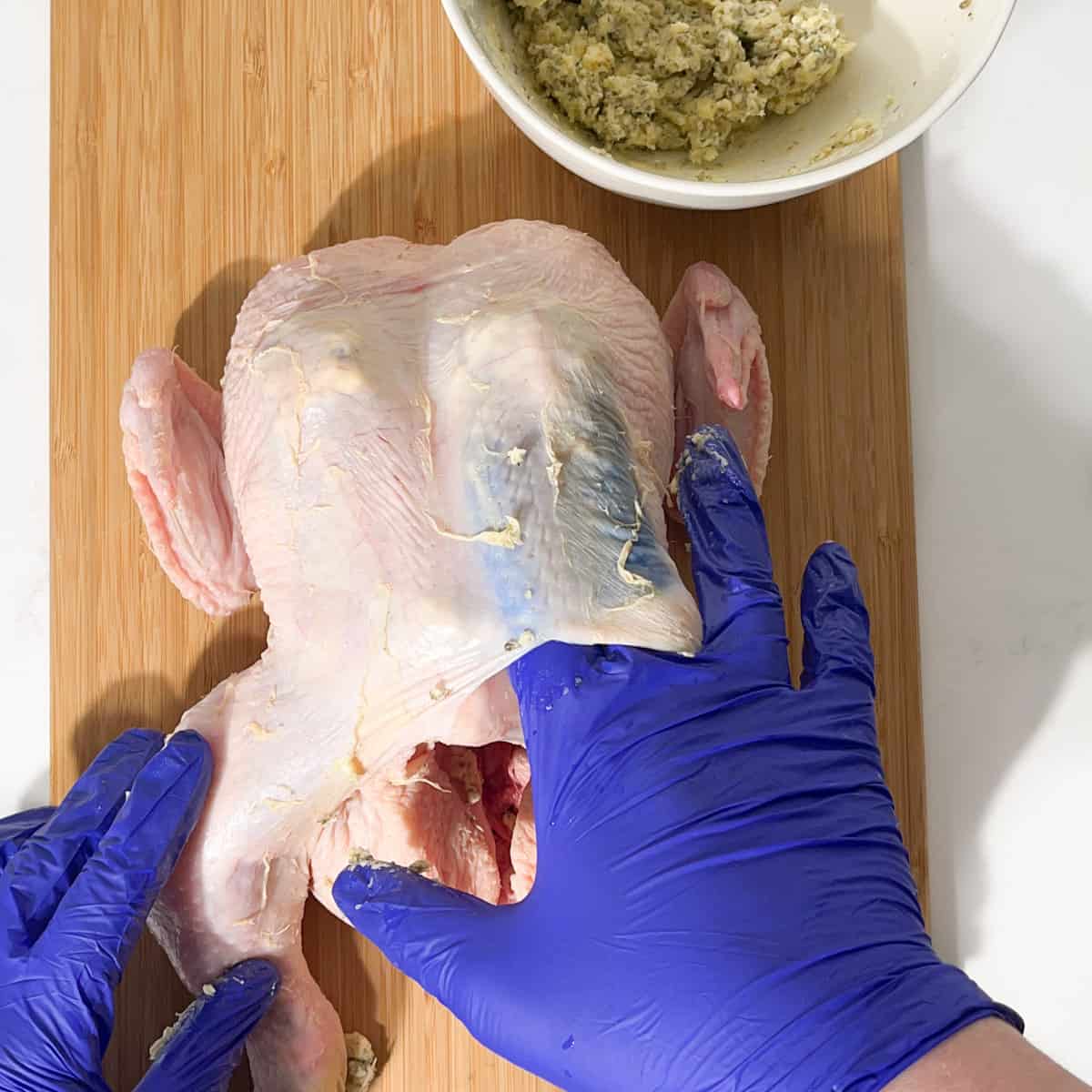 Stuffing compound butter under the skin of the Greek roast chicken.