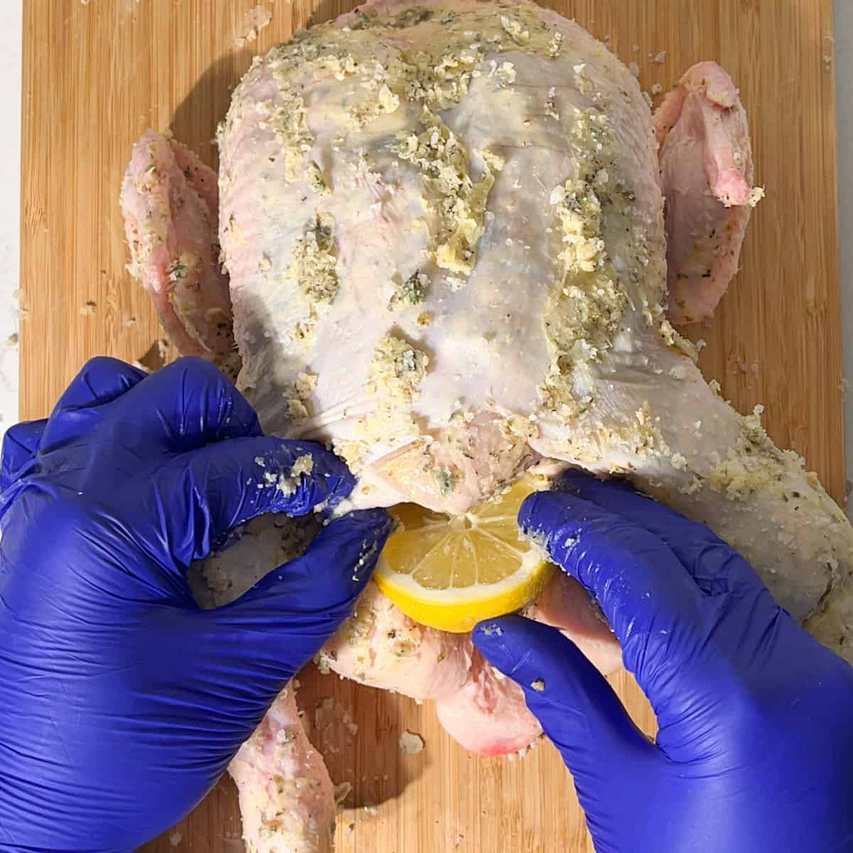Stuffing half a lemon into the cavity of the chicken.