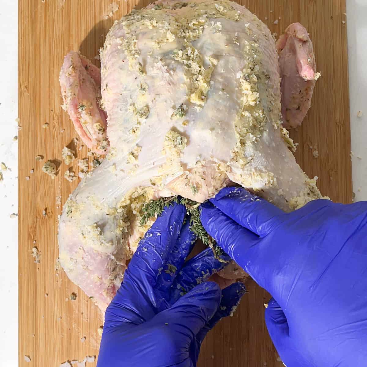 Stuffing thyme sprigs into the chicken cavity.