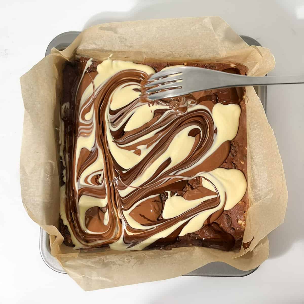 Swirling melted chocolate with a fork.