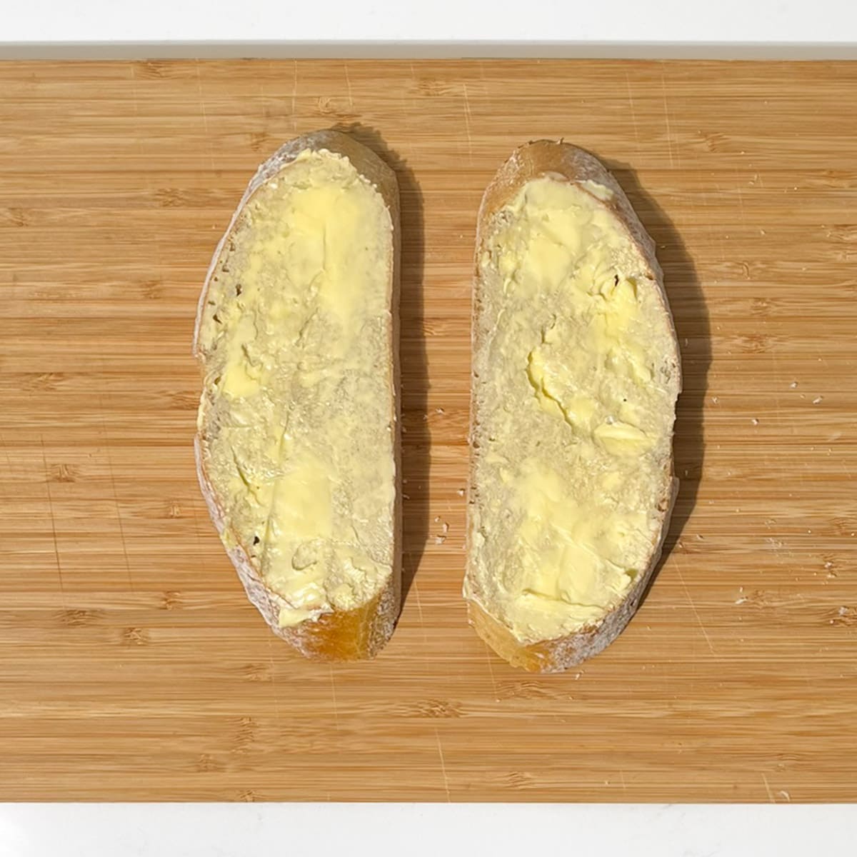 Two slices of buttered bread for the sourdough grilled cheese sandwich.