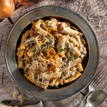 A plate of french onion pasta on a wooden background.