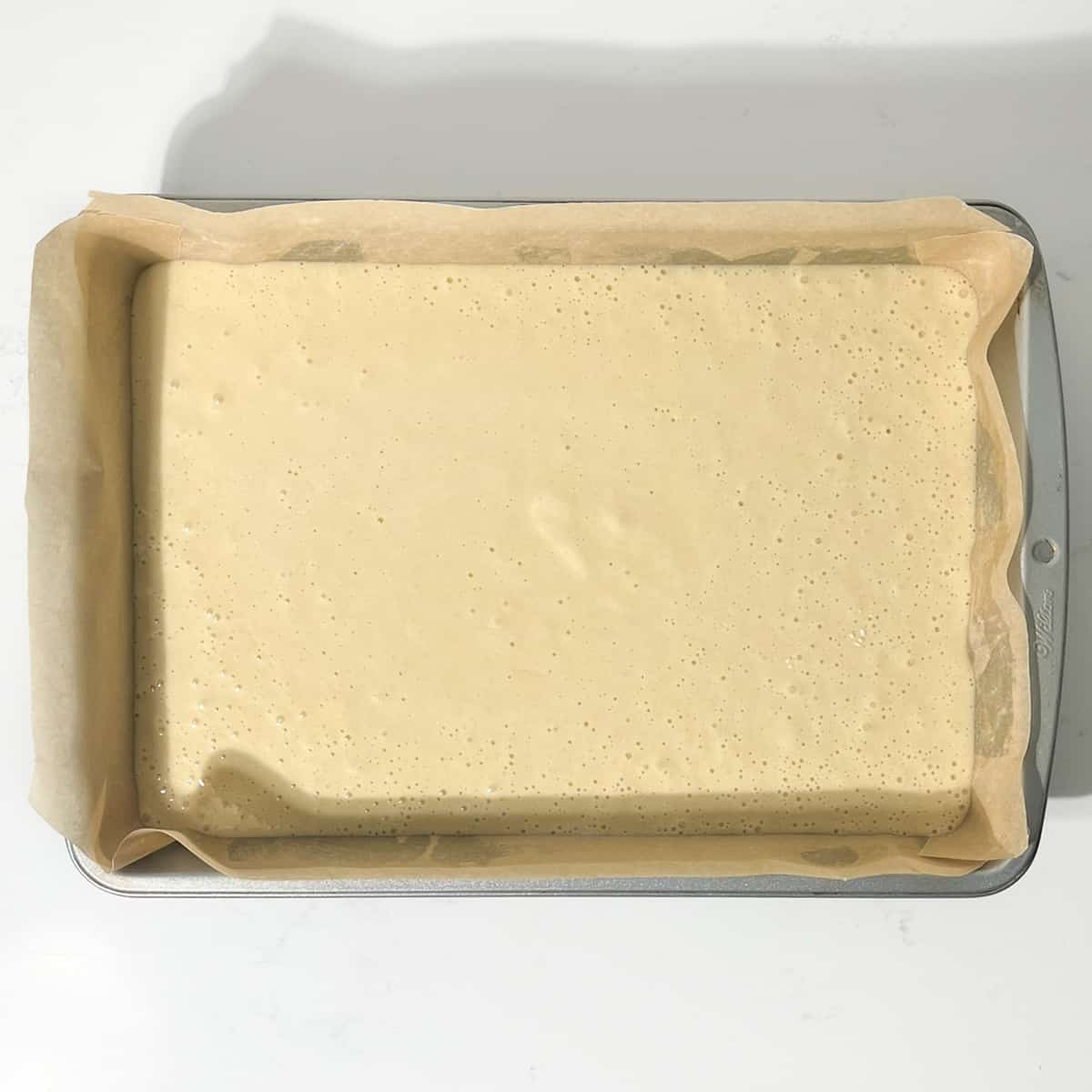 The batter for the vanilla tray bake in a rectangular baking tin.