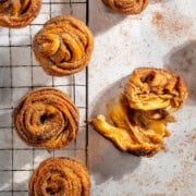 Cinnamon sugar cruffins made with crescent roll dough on a wire rack, with one broken open to show the flaky layers.