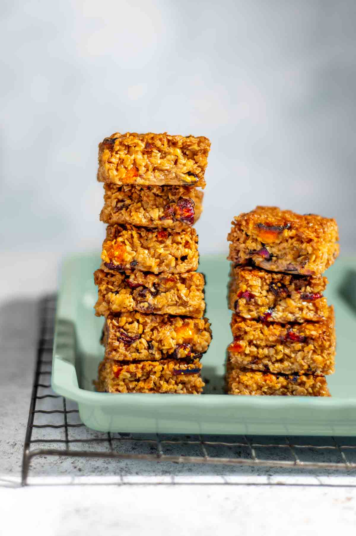 Two stacks of fruity flapjacks on a green baking tray.