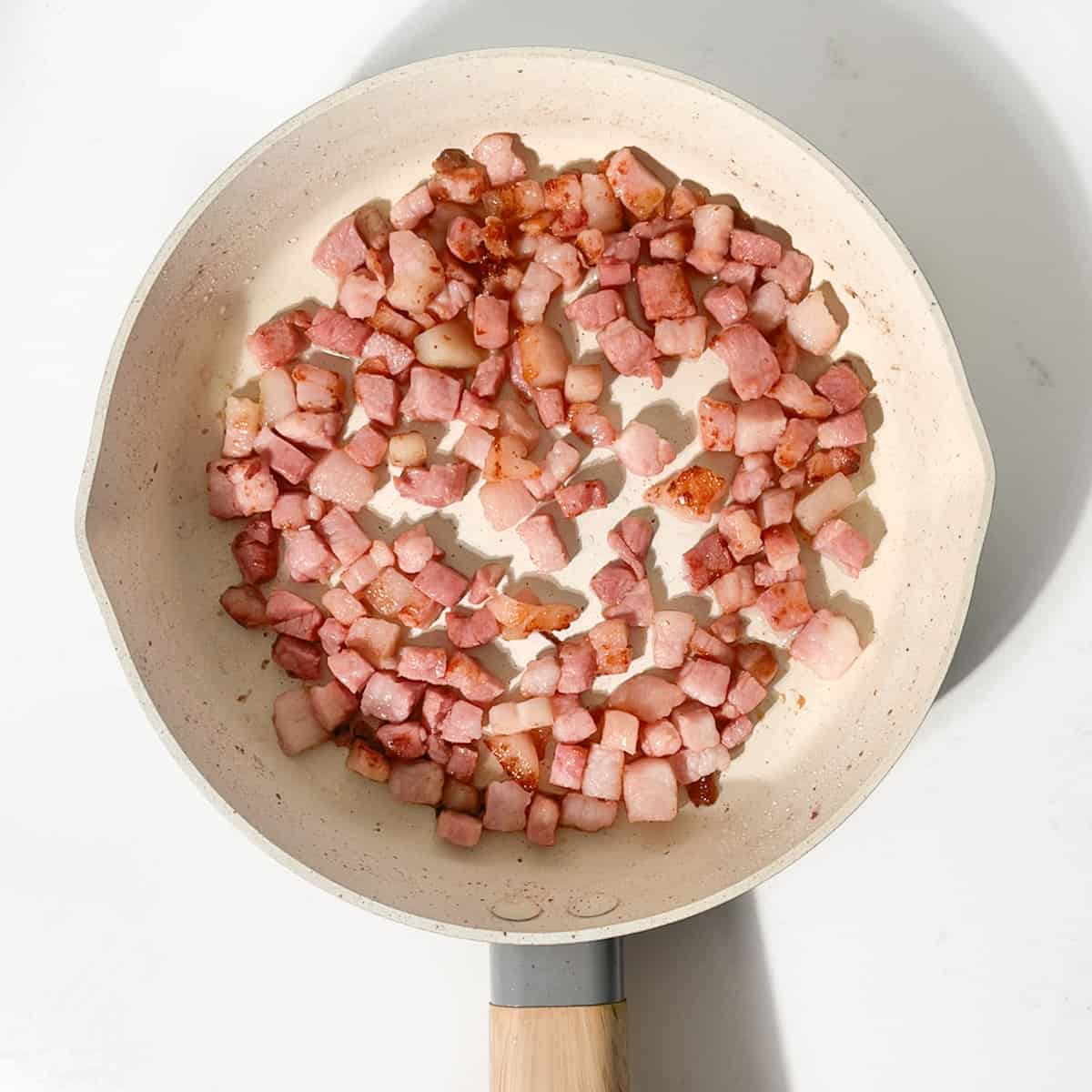 Frying pancetta in a small pan.