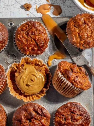 Date muffins in a muffin baking tray with caramel spread.