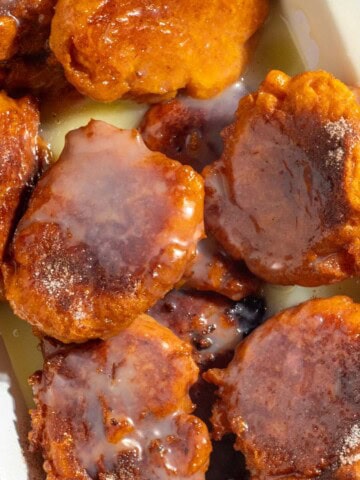 Pumpkin fritters (pampoenkoekies) with caramel sauce in a rectangular enamel dish.