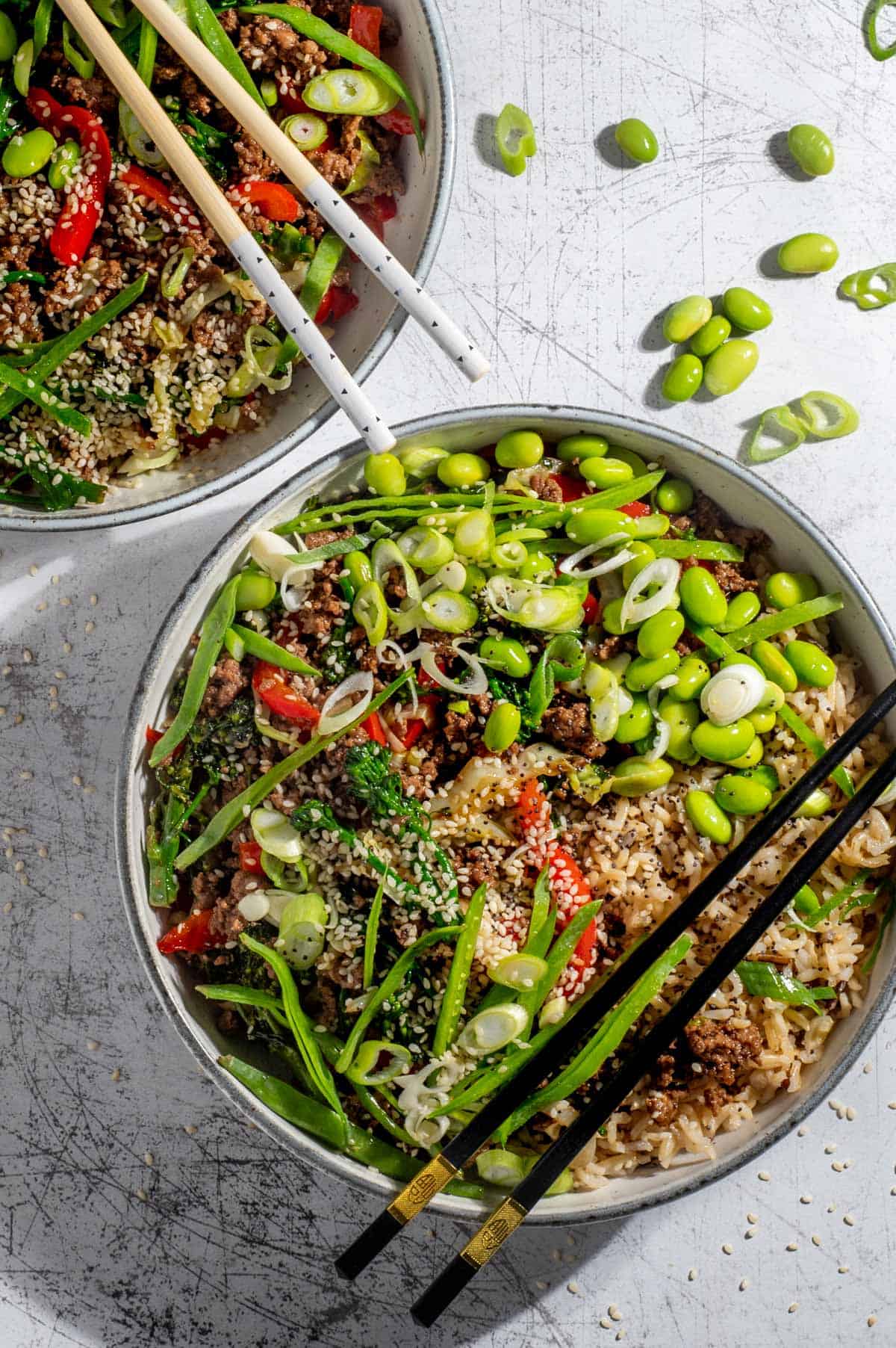 Two beef teriyaki bowls on a white background with chopsticks.