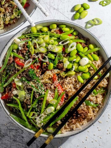 Two beef teriyaki bowls on a white background with chopsticks.