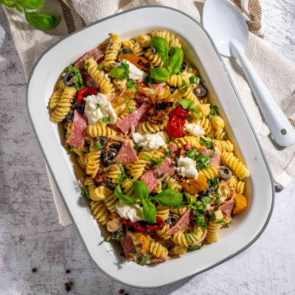 Creamy italian pasta salad in a rectangular enamel bowl.