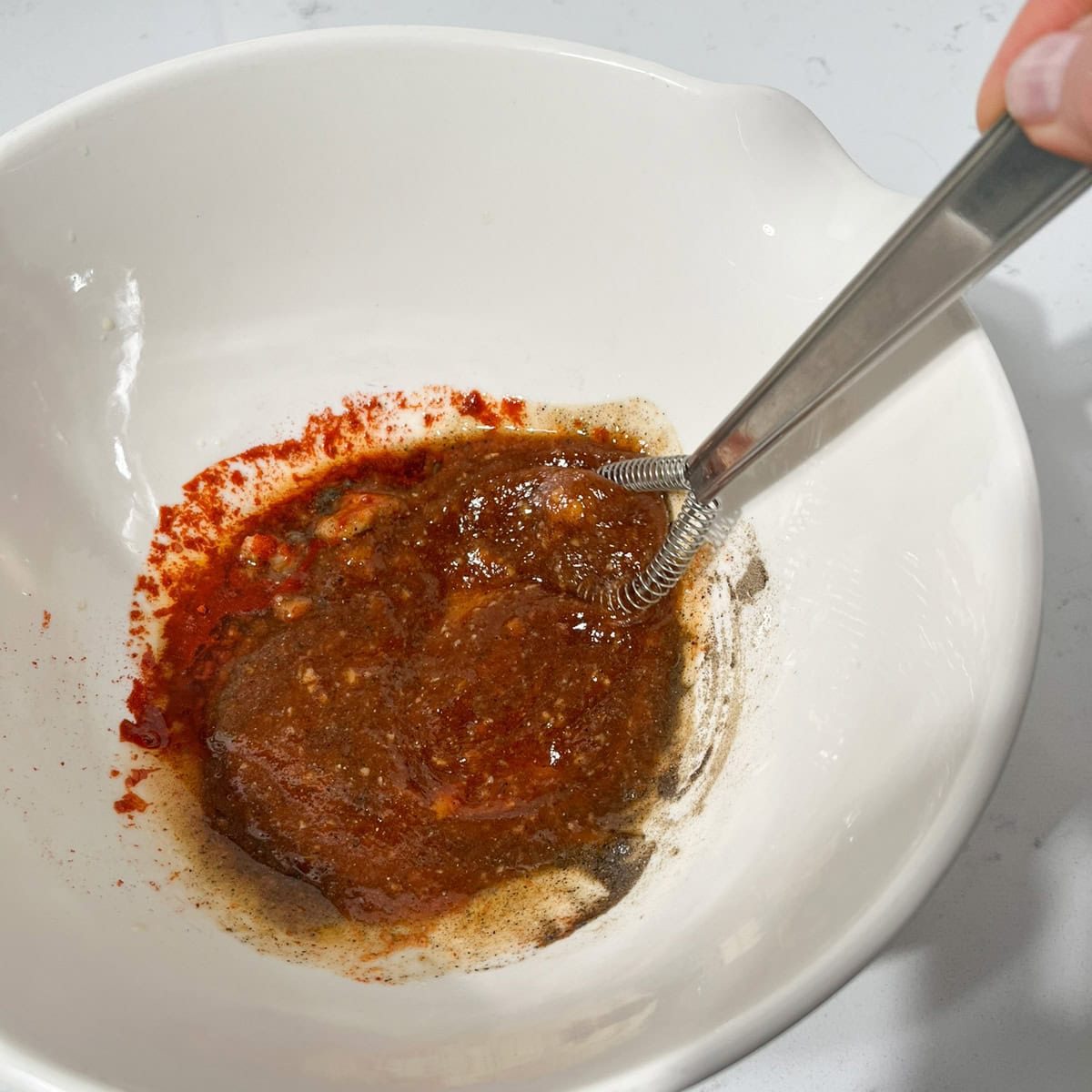 Whisking the ingredients for the marinade for the bang bang chicken skewers.