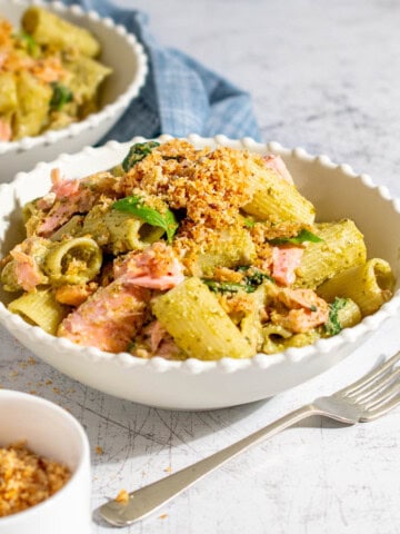 Pasta with salmon and pesto in two bowls on a white background.