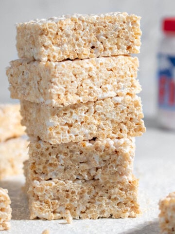 Squares of rice krispie treats with marshmallow fluff on a white background.