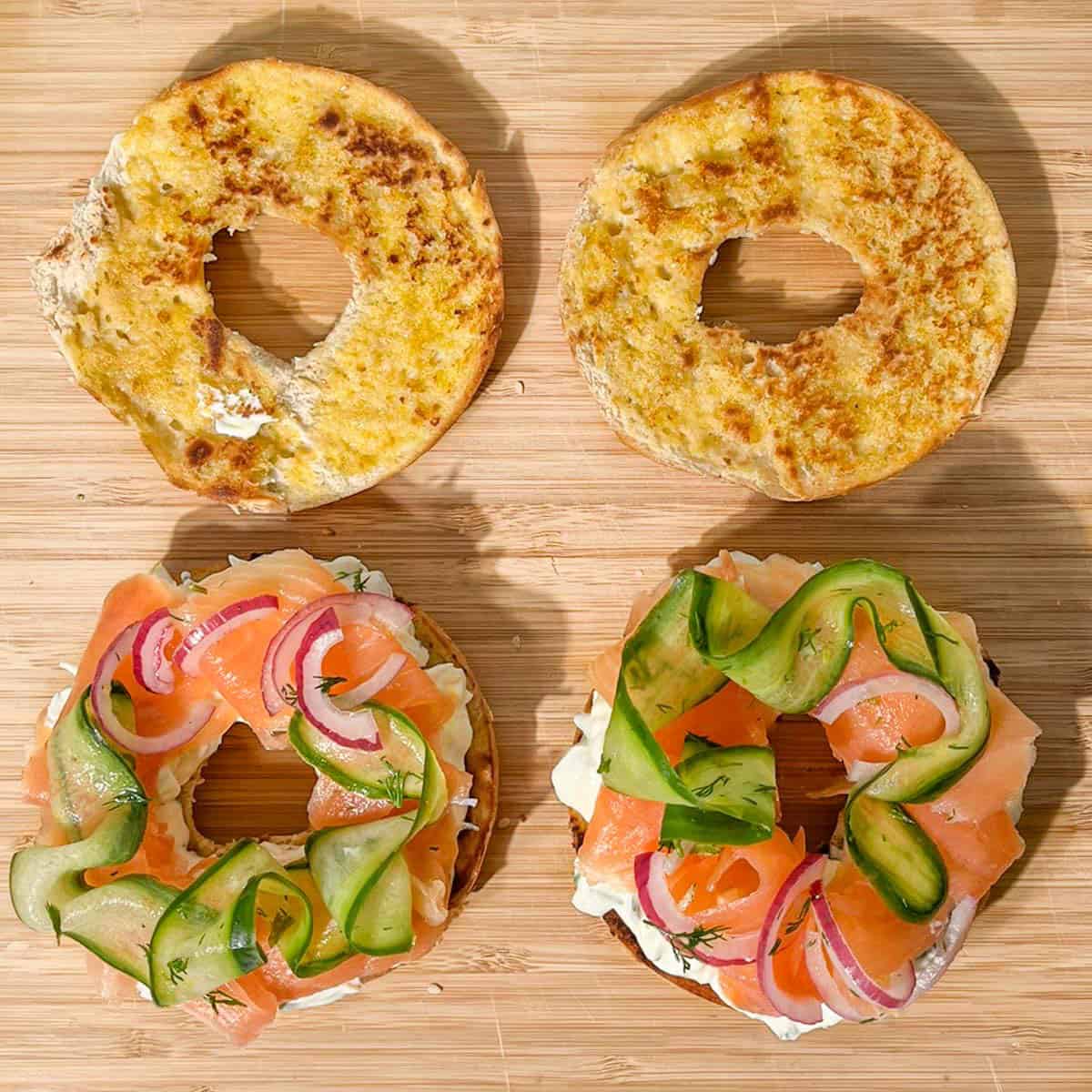 Two bagel halves layered with cream cheese, smoked salmon and cucumber pickle.