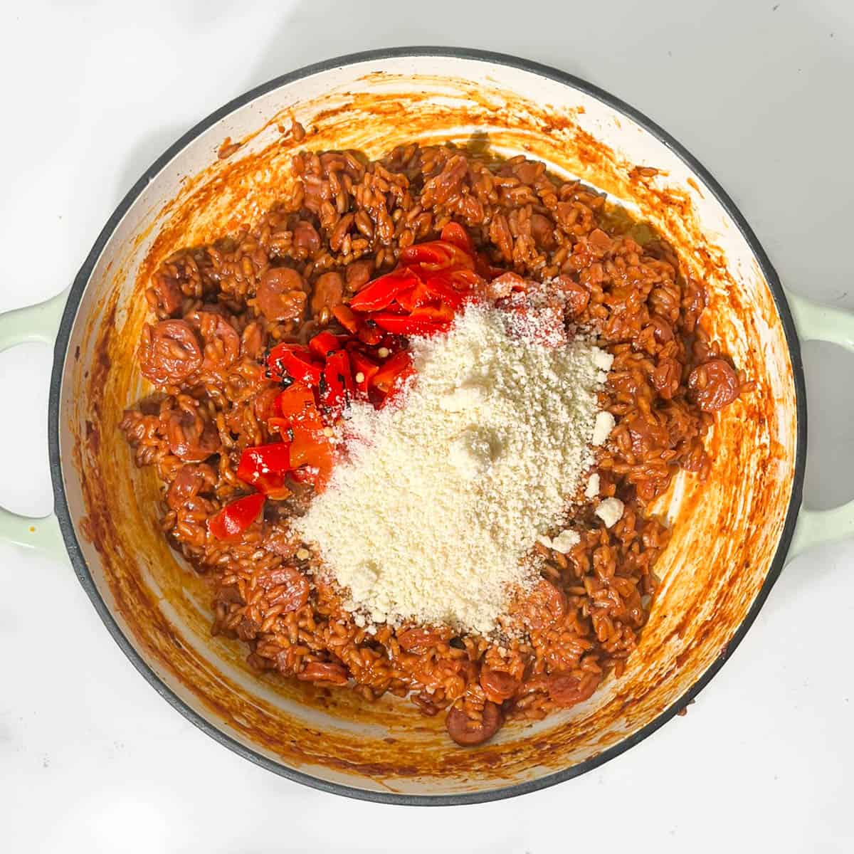 Adding sliced roasted peppers and parmesan to the chorizo risotto.