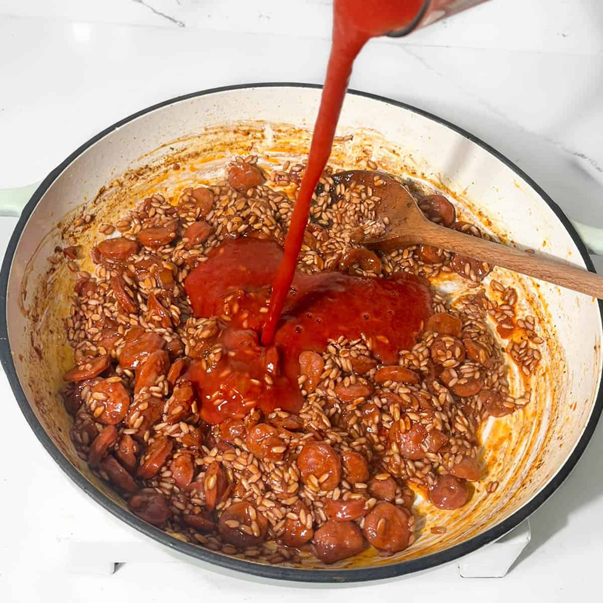 Adding passata to the chorizo risotto.