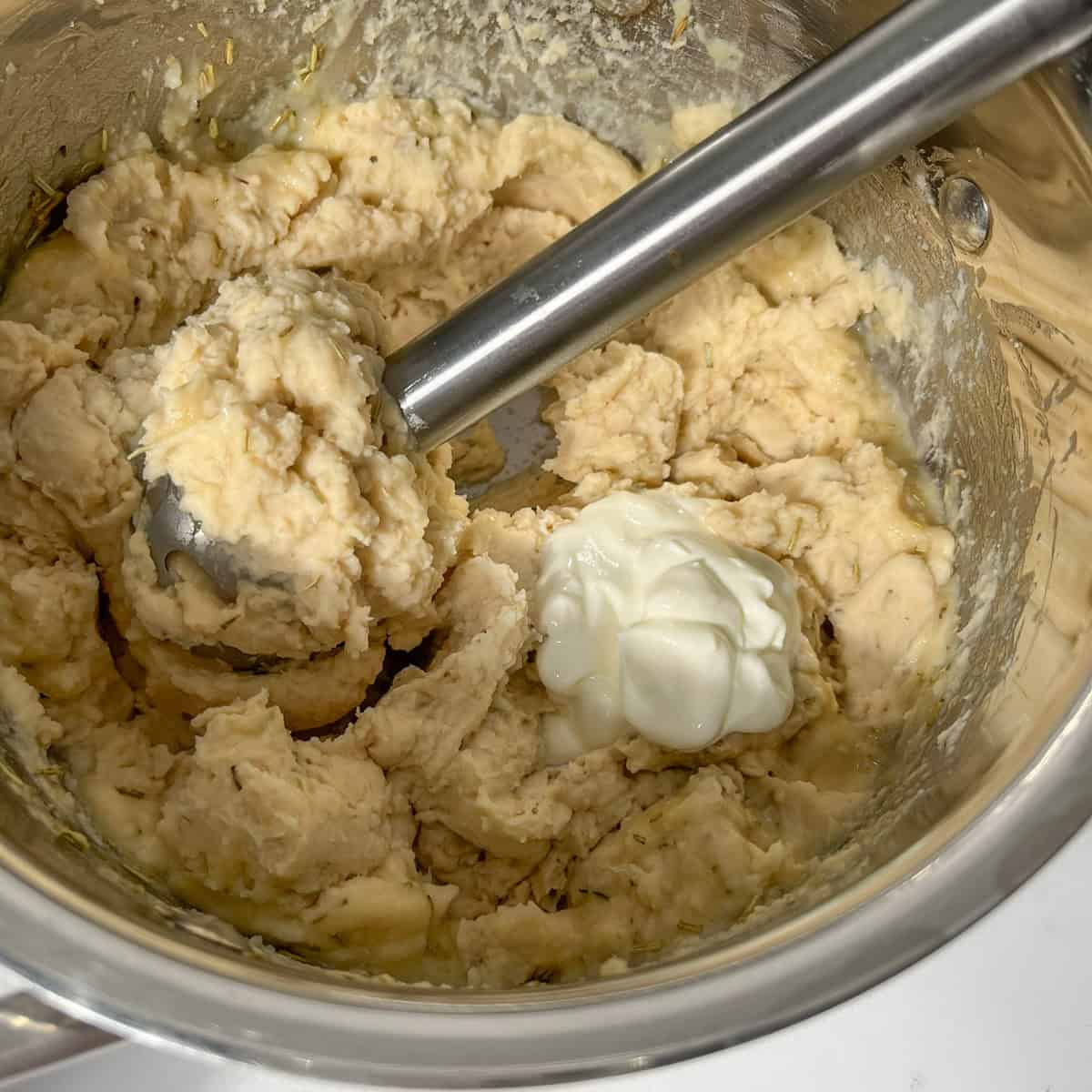Adding yoghurt to the butter bean mash.