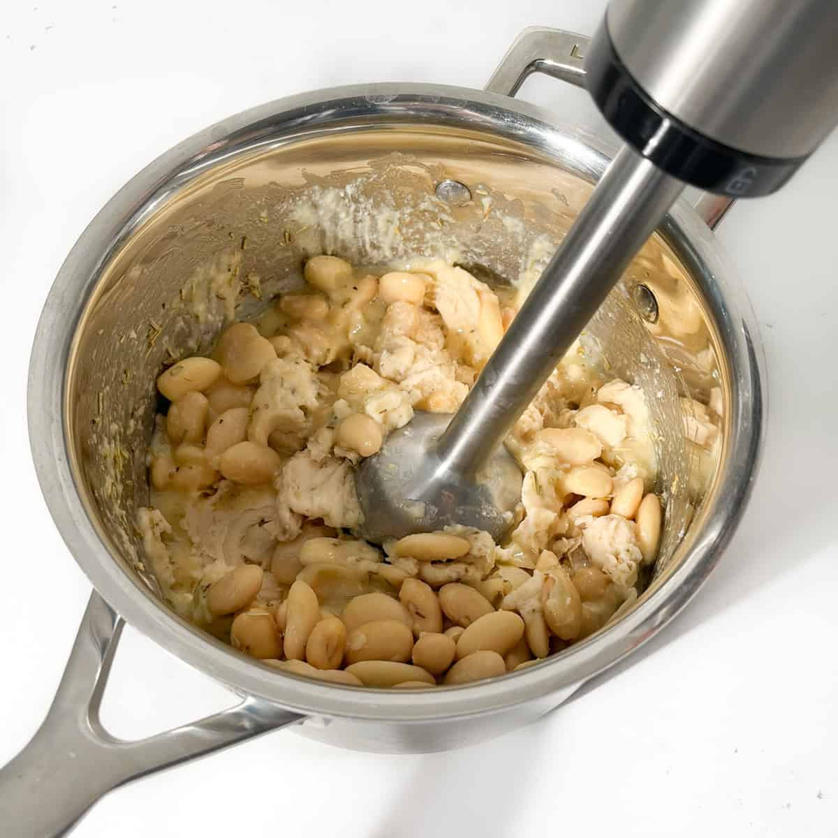 Using a stick blender to mash the butter beans.