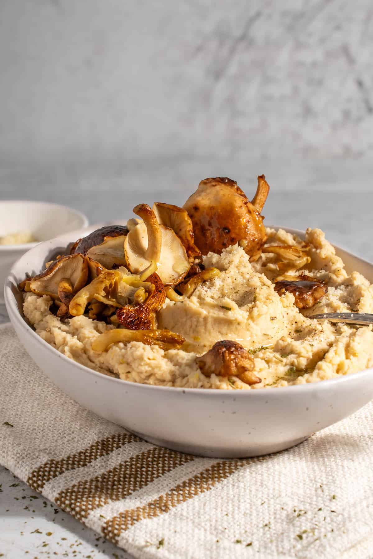 Butter bean mash in a white bowl on a neutral coloured tea towel.