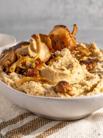 Butter bean mash in a white bowl on a neutral coloured tea towel.