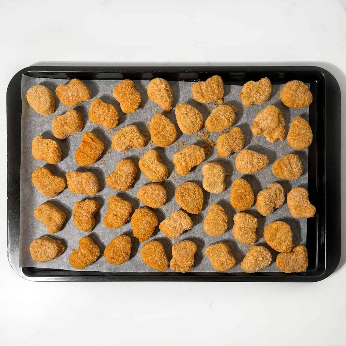 Chicken nuggets on a baking tray.