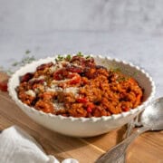 Chorizo risotto in a white bowl on a wooden board.