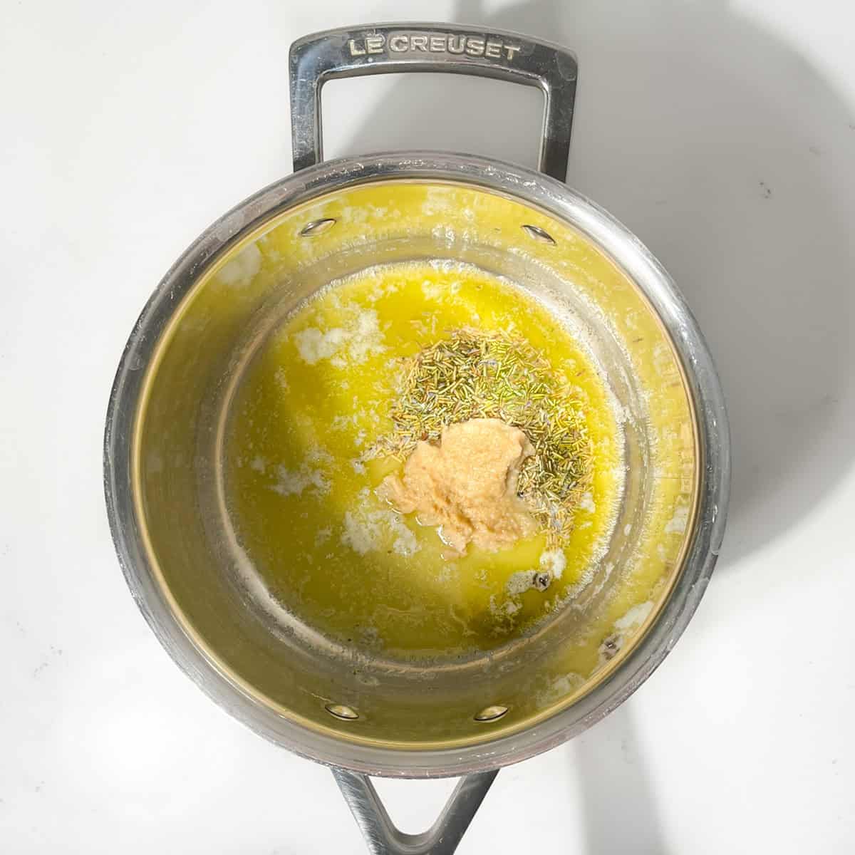 Melting the olive oil and garlic in a large saucepan.