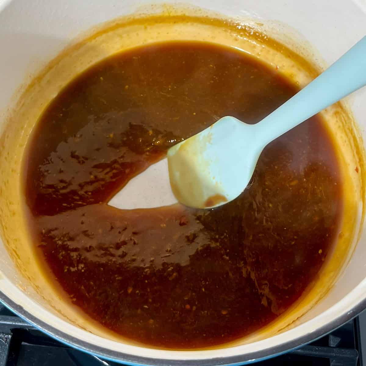 Checking the consistency of the orange chicken sauce.