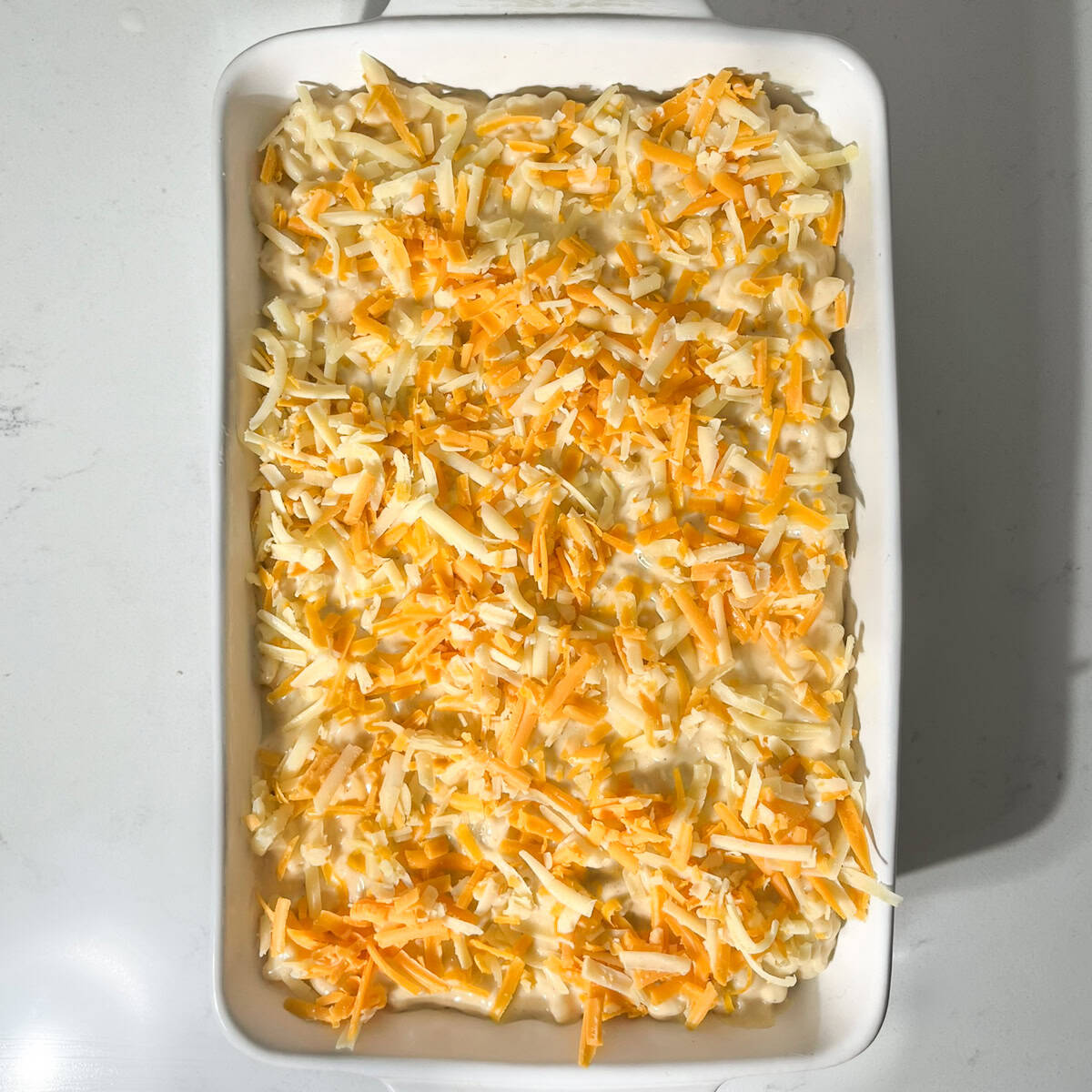 Three cheese mac and cheese in a large white oven dish, ready to go into the oven.
