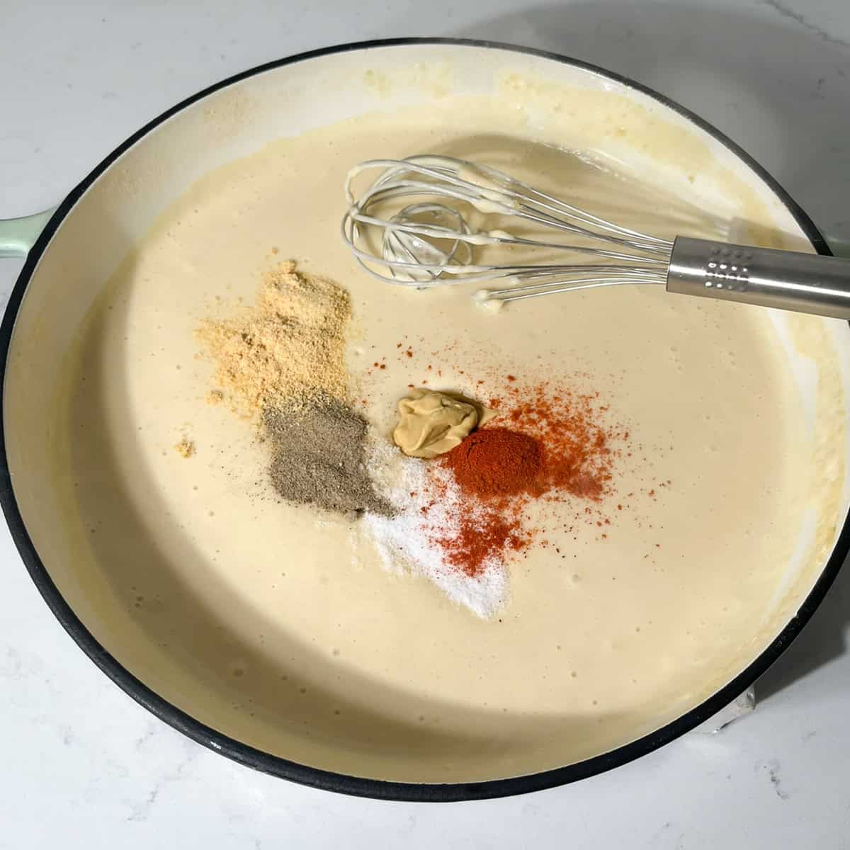 Adding the spices to the white sauce for the three cheese mac and cheese.