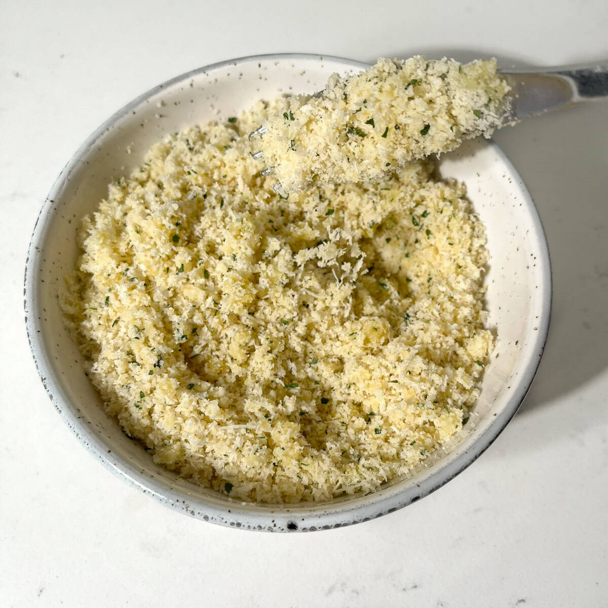 Mixing the parmesan and breadcrumbs in a bowl for the crumbed parmesan topping.