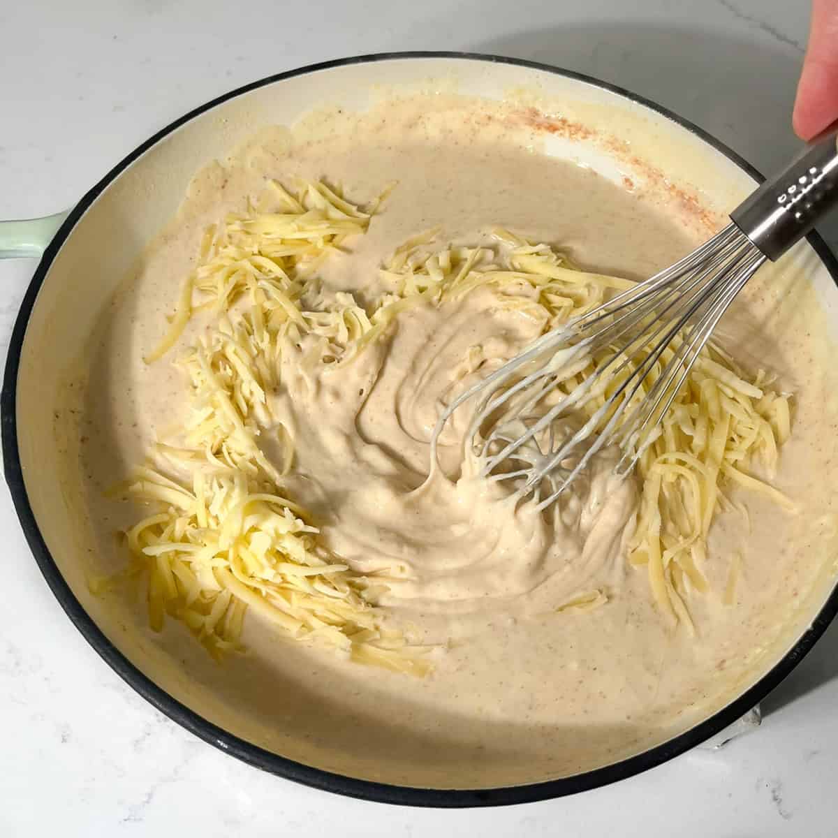 Mixing the cheese into the white sauce for the baked macaroni and cheese.