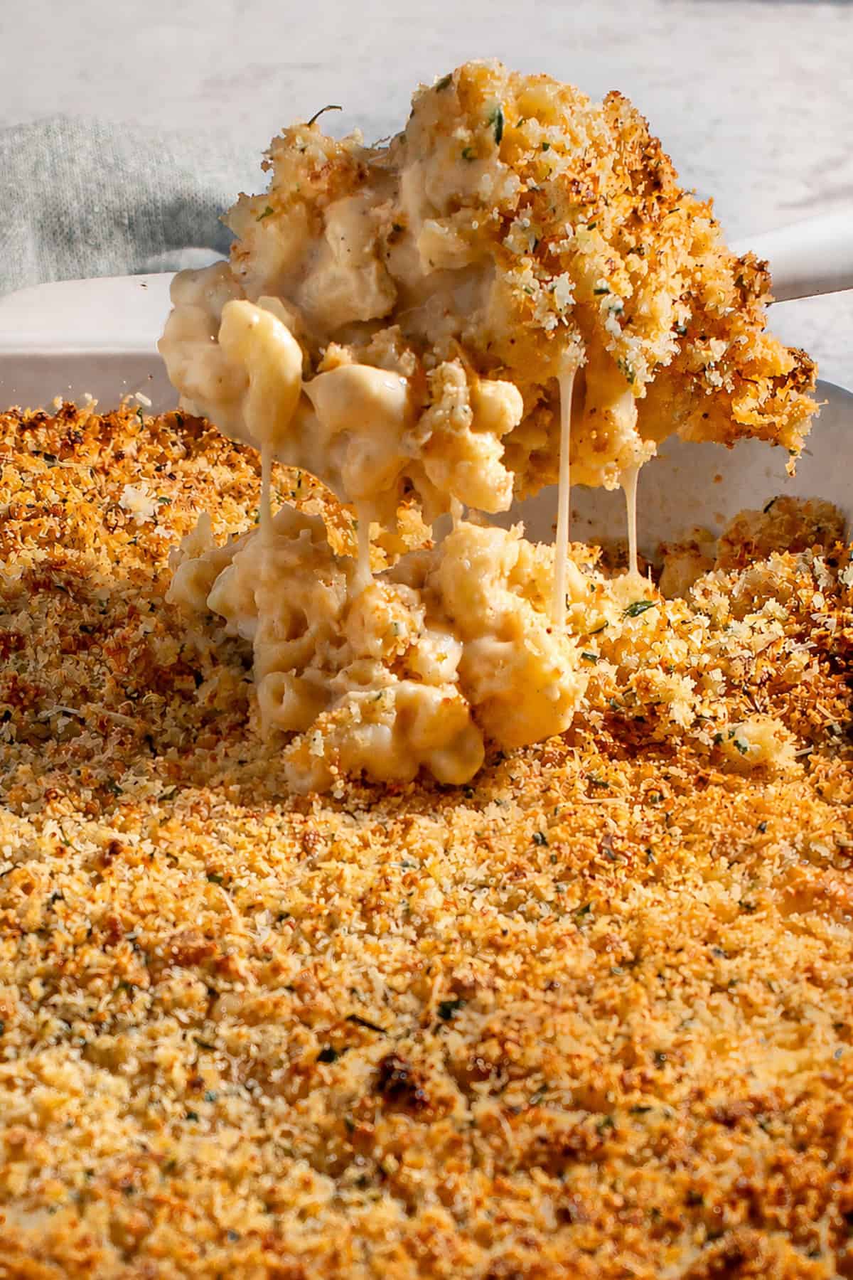 A scoop of baked three cheese mac and cheese with crispy garlic Parmesan crumb topping.